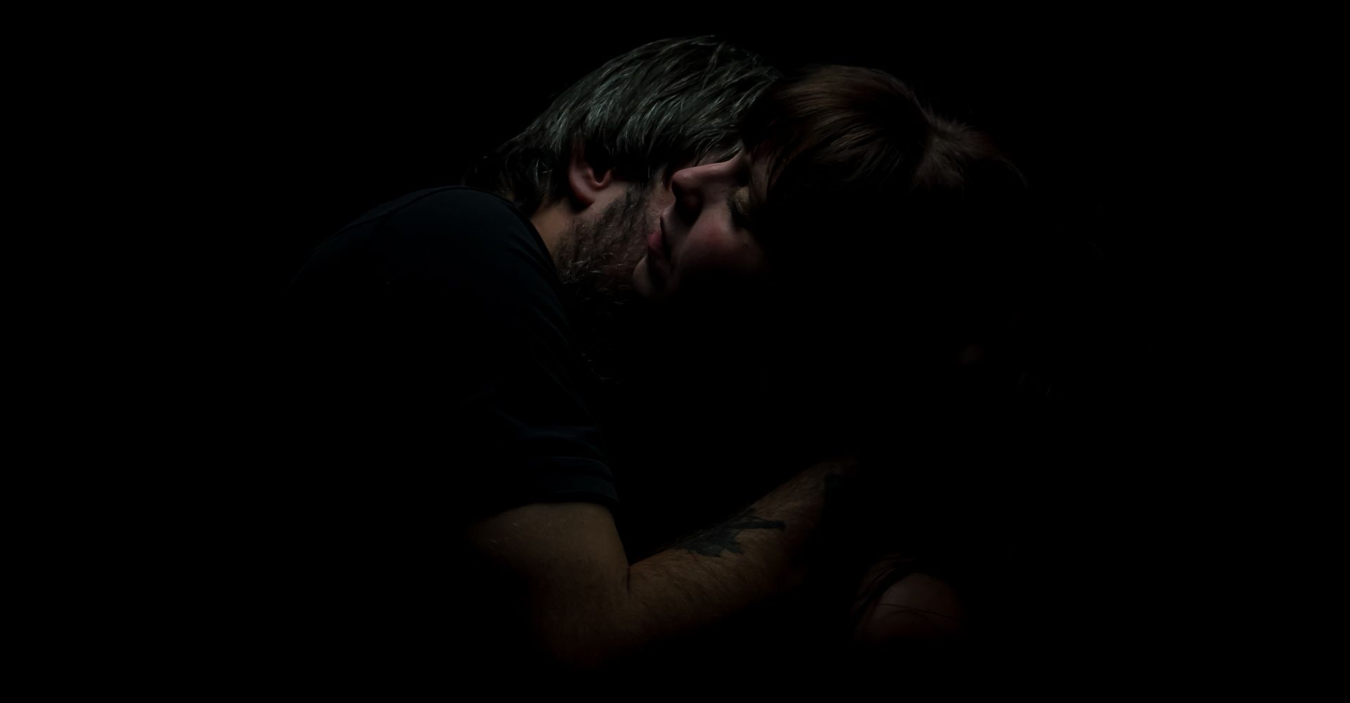 A couple embracing in low light